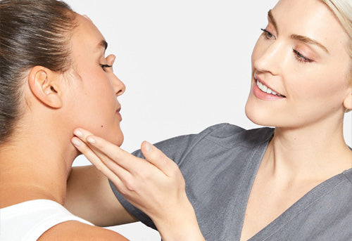 Skin therapist inspects woman's face 