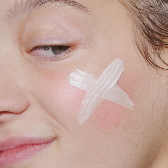 Woman with skin care product on her cheek