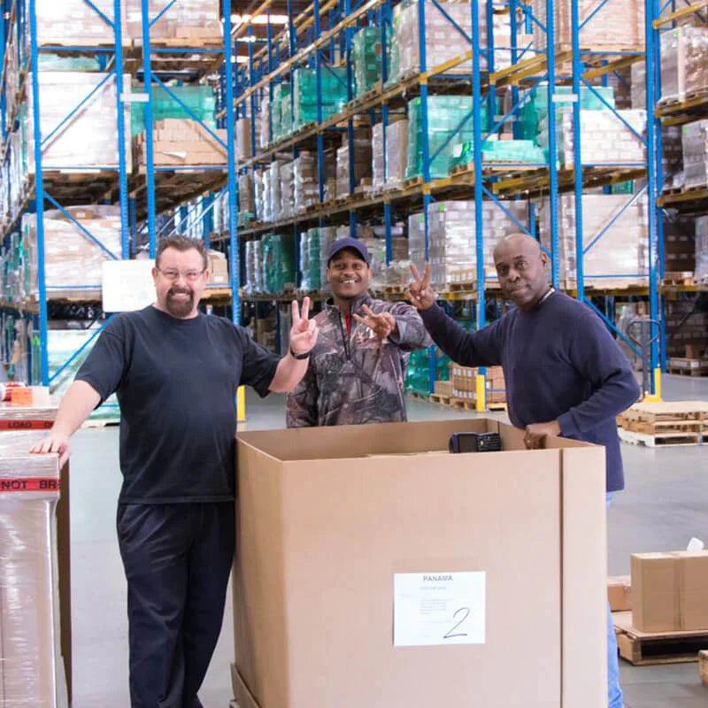 Three men pose for a picture in a warehouse environment